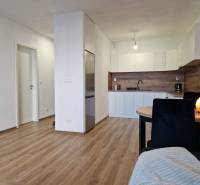Küche und Essbereich in einer 2-Zimmer-Wohnung mit Holzboden und weißen Möbeln.
