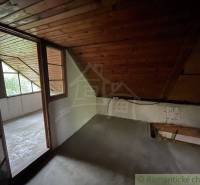 Ein Dachzimmer mit Holzverkleidung und einer verglasten Wand in einem Einfamilienhaus.