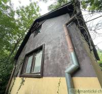 Ein Einfamilienhaus in Branč mit Putz, Kletterpflanzen und Holzfenstern.