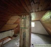 Dachboden in einem Einfamilienhaus mit Holzverkleidung und Balken, erhellt durch ein Fenster.
