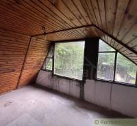 Dachgeschosszimmer in einem Einfamilienhaus mit Holzverkleidung und großen Fenstern.