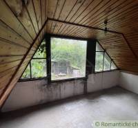 Ein Dachzimmer in einem Einfamilienhaus mit Holzverkleidung und Blick auf den Garten.