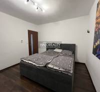 Schlafzimmer in einem Einfamilienhaus mit Bett, dunklem Boden und Bild an der Wand.