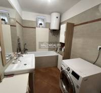 Badezimmer in einem Einfamilienhaus mit Dusche, Waschmaschine und Waschbecken.