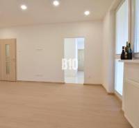 Ein helles Zimmer mit Holzboden in einer 3-Zimmer-Wohnung, beleuchtet mit Deckenleuchten.