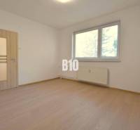 Helles Zimmer mit Holzböden und Fenster in einer 3-Zimmer-Wohnung.