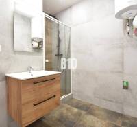 Badezimmer in einer 3-Zimmer-Wohnung mit einem Holzschrank, einer Duschkabine und einem Wassererhitzer.