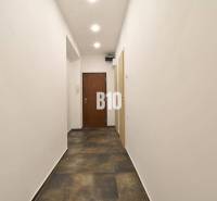 Ein Flur mit weißen Wänden und dunklem Boden in einer 3-Zimmer-Wohnung.