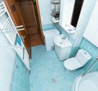 Badezimmer in einer 2-Zimmer-Wohnung mit Waschmaschine, Duschkabine, Waschbecken und Spiegel.