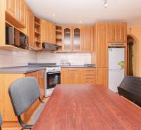 Küche in einer 2-Zimmer-Wohnung mit einer Holzküchenzeile und einem Esstisch.