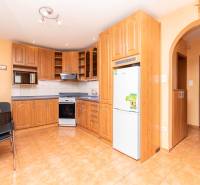 Küche in einer 2-Zimmer-Wohnung mit Holzküche, Mikrowelle und Herd auf Fliesen.