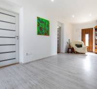 Innenraum eines Einfamilienhauses mit weißen Wänden, Holztüren und einem bunten Gemälde.