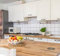 Küche im Einfamilienhaus mit hellen Schränken, Holzarbeitsplatte, Obst und Kräutern.