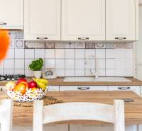 Küche in einem Einfamilienhaus, weiße Schränke, Holzarbeitsplatte, Obstkorb.
