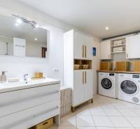 Geräumiges Badezimmer mit Waschmaschine und Trockner in einem Einfamilienhaus, mit hellem Interieur.
