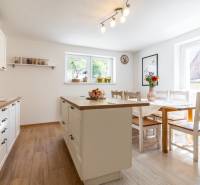Küche in einem Einfamilienhaus mit Tisch, Insel und Accessoires auf Holzboden.