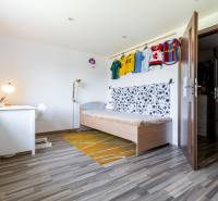 Kinderzimmer in einem Einfamilienhaus mit Bett, Schreibtisch und Fußballtrikots an der Wand.