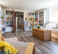 Wohnzimmer in einem Einfamilienhaus mit Bibliothek, hellen Möbeln und Pflanzen.