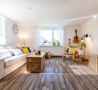 Helles Wohnzimmer mit Sofa, Gitarre an der Wand und Holzboden. Einfamilienhaus.