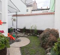Ein kleiner Garten bei einer 2-Zimmer-Wohnung mit Pflastersteinen, Pflanzen und Steindekoration.