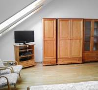 Dachfenster, Holzmöbel und Fernseher im Wohnzimmer einer 2-Zimmer-Wohnung.