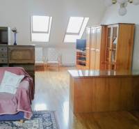 Dachgeschoss-Wohnzimmer mit Holzmöbeln und Dachfenstern in einer Zweizimmerwohnung.