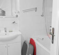 Badezimmer in einer 2-Zimmer-Wohnung mit Badewanne und Waschbecken, weiße Fliesen.