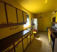 Eine Küche in einem Einfamilienhaus mit gelben Wänden und Schränken, der Raum ist hell und funktional.