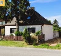 Einfamilienhaus in Hundsheim mit weißer Fassade, Holzzaun und umgebendem Grün.