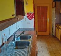 Küche in einem Einfamilienhaus mit gelben Schränken und einem Spülbecken aus Edelstahl.
