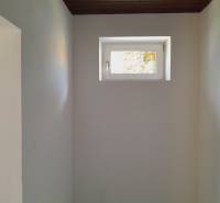 Malé Fenster in engen Geschäftsräumen, weiße Wände, dunkle Decke.