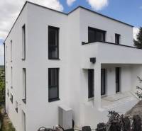 Eine Villa in Hainburg an der Donau mit weißer Fassade, umgeben von Grün und blauem Himmel.