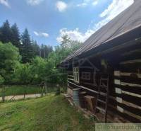 Eine Hütte in Zákopčí, umgeben von Wald, Holzwände, Zaun und blauer Himmel.