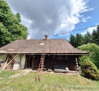 Rustikale Hütte in Zákopčie, umgeben von Wäldern und dramatischen Wolken am Himmel.