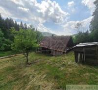 Eine Holzhütte in Zákopčí, umgeben von Wäldern und blauem Himmel.