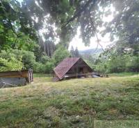 Eine Hütte in Zákopčí, umgeben von grüner Natur und Hügeln im Hintergrund.