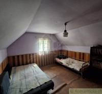Ein Zimmer in einer Hütte mit Betten und einem Bücherregal, Holzwandverkleidung.