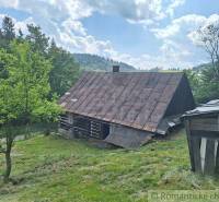 Holzhütte in Zákopčí am Hang, umgeben von Bäumen und blauem Himmel.