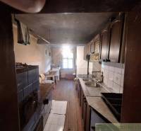 Eine Küche in einer Hütte mit Holzverkleidung, einem Kachelofen und einem Waschbecken.