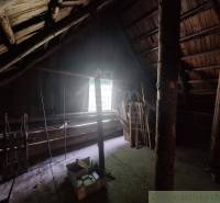 Das Dachgeschoss der Hütte mit Holzbalken und einem Fenster, das den Raum beleuchtet.