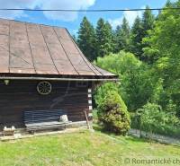 Eine Hütte in Zákopčí, umgeben von Wäldern, mit einer Bank und Holzelementen.