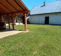 Garten bei der Hütte in Tužina mit Unterstand und Rasen an einem sonnigen Ort.