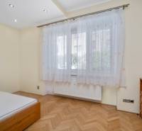 Helles Schlafzimmer mit Vorhängen und Holzmöbeln in einer 3-Zimmer-Wohnung.