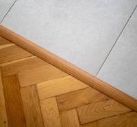 Übergang zwischen Holzboden und weißen Fliesen in einer 3-Zimmer-Wohnung.
