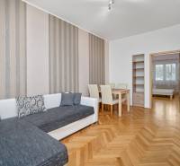 Wohnzimmer mit orangefarbenen Holzmöbeln, Sofa und Esstisch in einer 3-Zimmer-Wohnung.