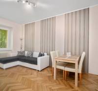 Wohnzimmer mit Ecksofa, Tisch und Parkettboden in einer 3-Zimmer-Wohnung.