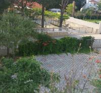 Der Garten des Einfamilienhauses in Vrsi mit Pflastersteinen, Grünflächen und Blumen.
