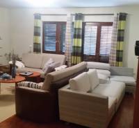 Wohnzimmer mit bequemen Sofas, Holzmöbeln und Vorhängen in einem Einfamilienhaus.