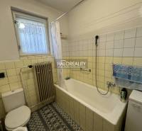 Ein Badezimmer in einem Einfamilienhaus mit Badewanne, Heizkörper und Fenster, dekoriert mit Fliesen.