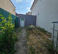 Das Einfamilienhaus in der Rybničná-Straße in Veľká Mača, ein schmaler Hof mit Grünflächen und einem Betonweg.